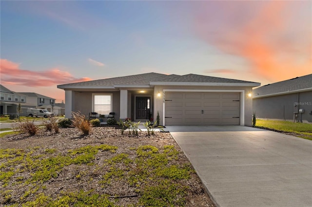 view of front of property with concrete driveway, an attached garage, and stucco siding