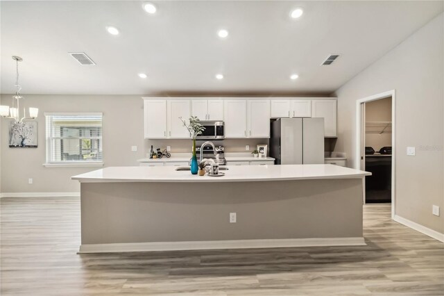 kitchen featuring visible vents, a kitchen island with sink, appliances with stainless steel finishes, and light countertops