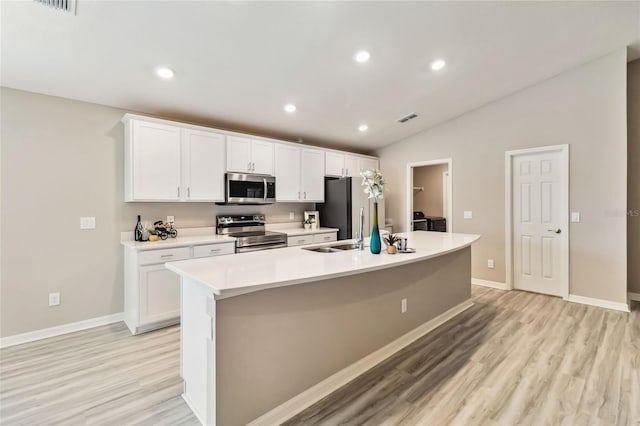 kitchen featuring a sink, visible vents, white cabinetry, appliances with stainless steel finishes, and an island with sink