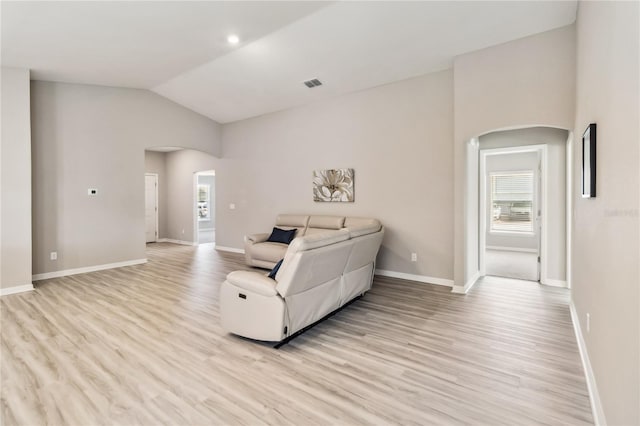 living area featuring arched walkways, light wood-type flooring, and visible vents