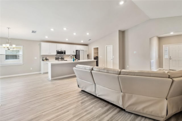 living room with a notable chandelier, lofted ceiling, recessed lighting, light wood-style floors, and baseboards