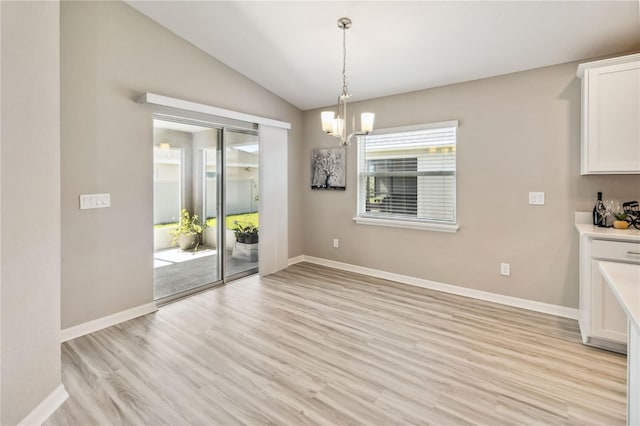 unfurnished dining area with lofted ceiling, baseboards, and light wood finished floors