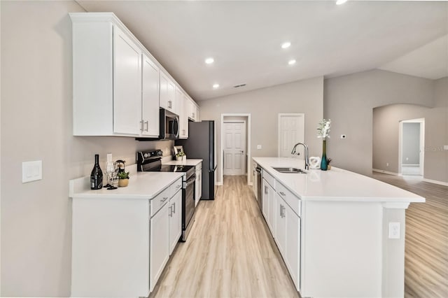 kitchen with appliances with stainless steel finishes, vaulted ceiling, light countertops, white cabinetry, and a sink