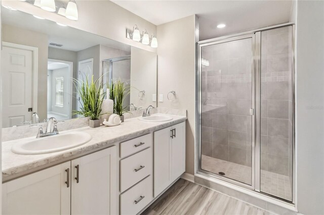 full bath featuring double vanity, a shower stall, visible vents, and a sink