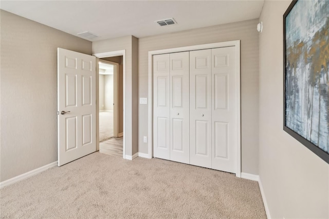 unfurnished bedroom with a closet, carpet, visible vents, and baseboards