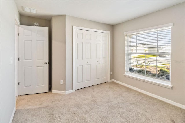 unfurnished bedroom featuring a closet, light carpet, and baseboards