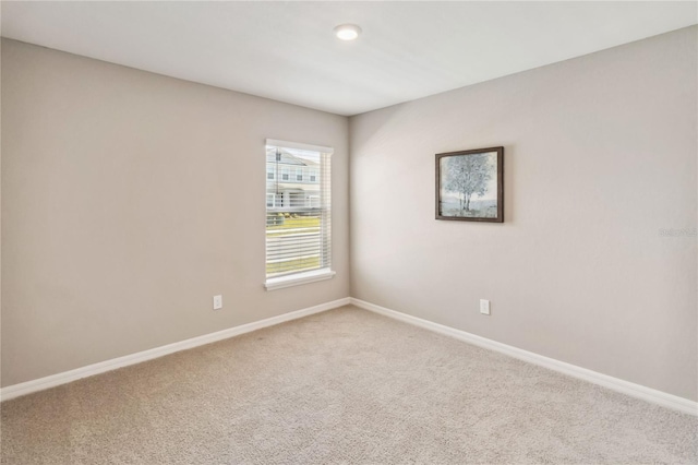 empty room featuring light carpet and baseboards