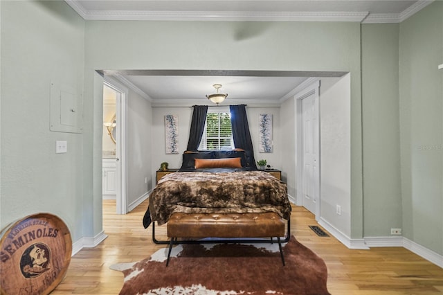 bedroom with light wood-style floors, visible vents, crown molding, and baseboards