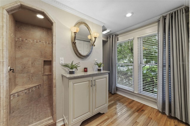 full bathroom featuring wood-type flooring, ornamental molding, walk in shower, and vanity