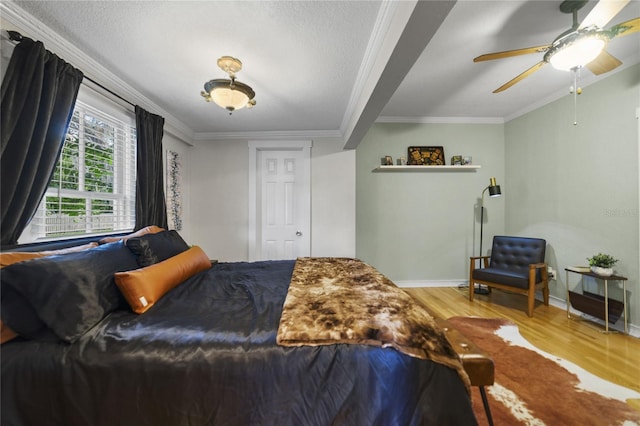 bedroom with ceiling fan, crown molding, baseboards, and wood finished floors