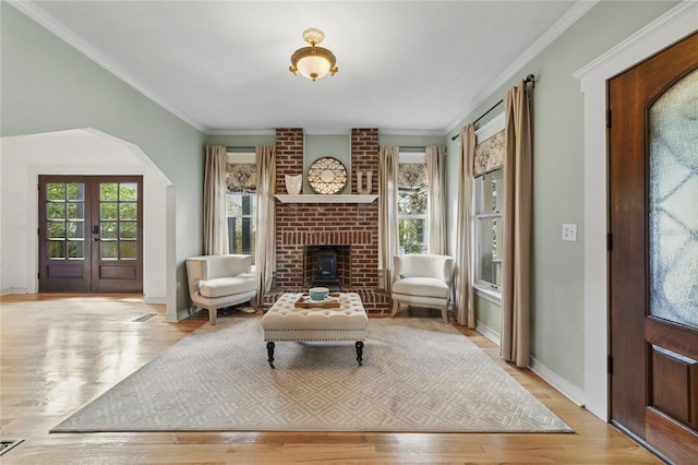 living area featuring ornamental molding, arched walkways, plenty of natural light, and wood finished floors