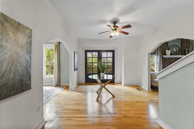 entryway featuring ornamental molding, visible vents, a textured ceiling, and light wood finished floors