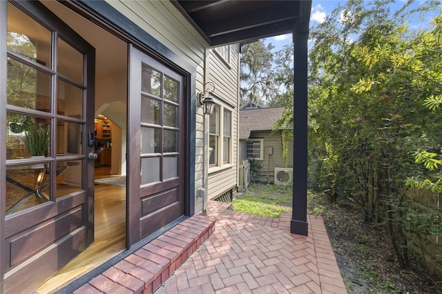 view of exterior entry featuring ac unit and a patio area