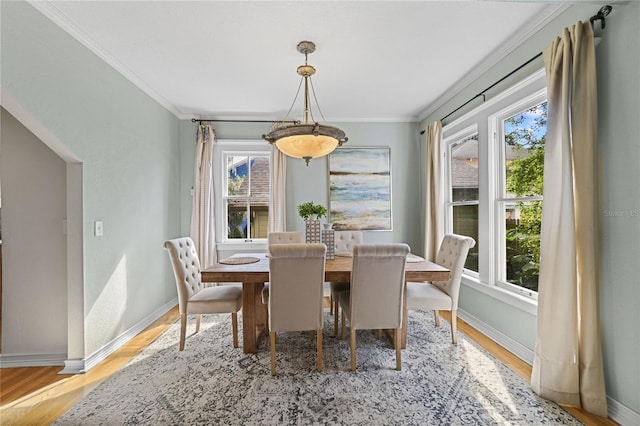 dining space with baseboards, crown molding, and wood finished floors