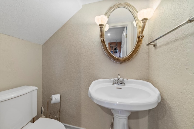 bathroom with a sink, a textured wall, and toilet