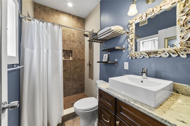 bathroom with toilet, visible vents, a tile shower, and vanity