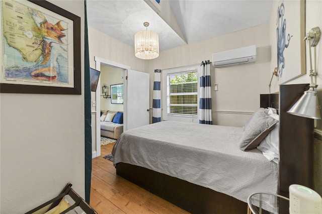 bedroom featuring a wall mounted air conditioner, a notable chandelier, and hardwood / wood-style flooring