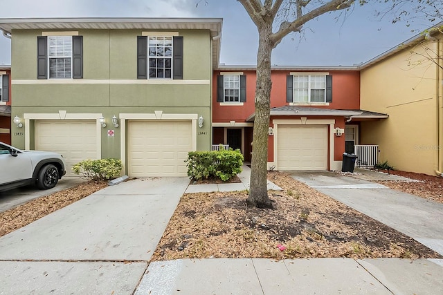 multi unit property featuring an attached garage, driveway, and stucco siding