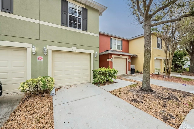 townhome / multi-family property with concrete driveway, a garage, and stucco siding