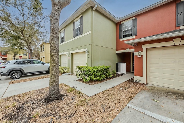 townhome / multi-family property with stucco siding, an attached garage, and driveway