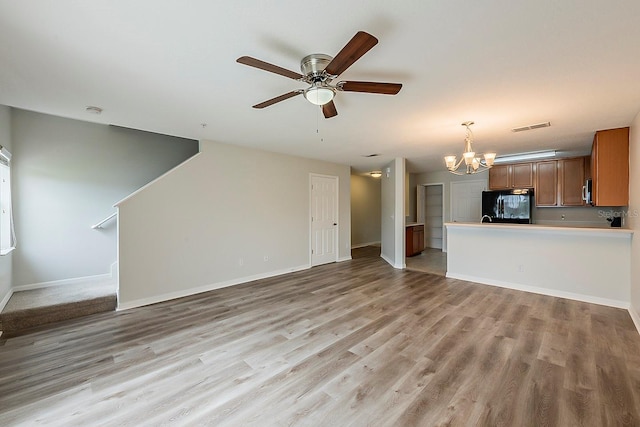 unfurnished living room featuring baseboards, ceiling fan with notable chandelier, visible vents, and light wood-type flooring