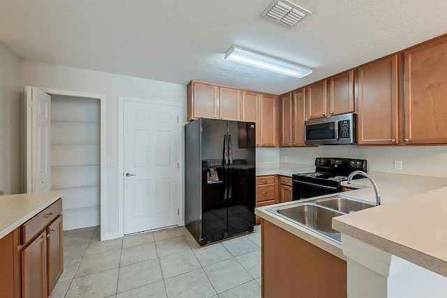 kitchen featuring visible vents, black appliances, a sink, light tile patterned flooring, and light countertops