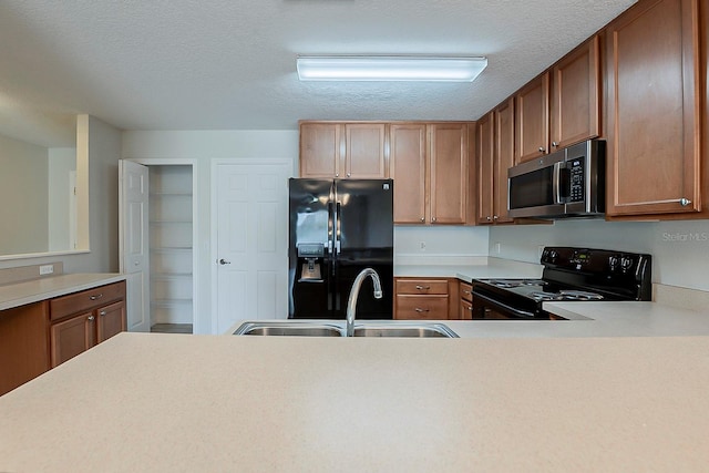 kitchen featuring a textured ceiling, black appliances, light countertops, and a sink