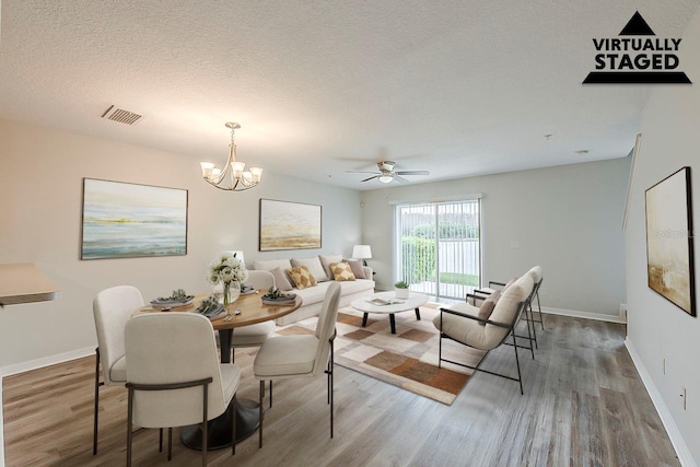 dining room with visible vents, a textured ceiling, wood finished floors, and a chandelier