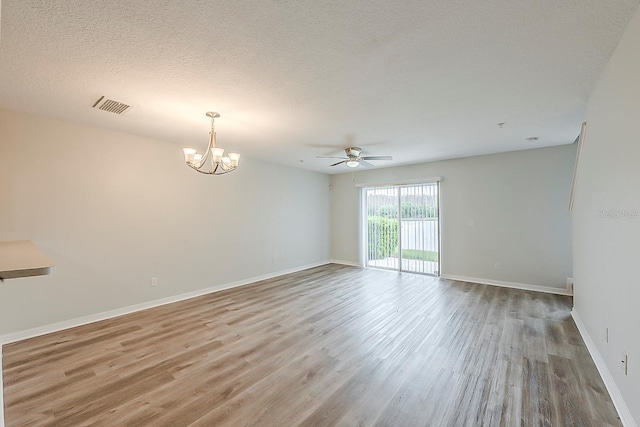 empty room featuring baseboards, wood finished floors, visible vents, and a textured ceiling