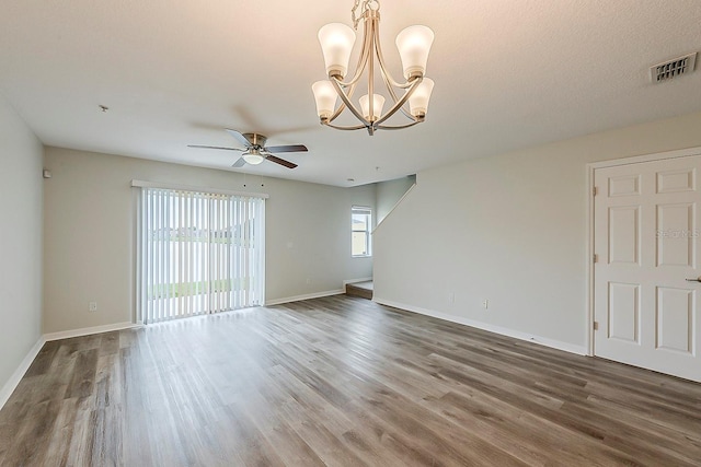 unfurnished room with ceiling fan with notable chandelier, wood finished floors, visible vents, and baseboards