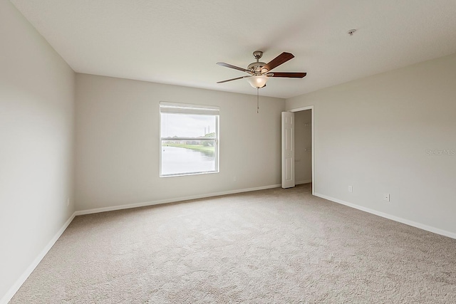 empty room featuring ceiling fan, baseboards, and carpet