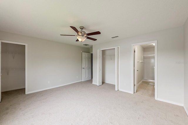 unfurnished bedroom with visible vents, light colored carpet, ensuite bathroom, and baseboards