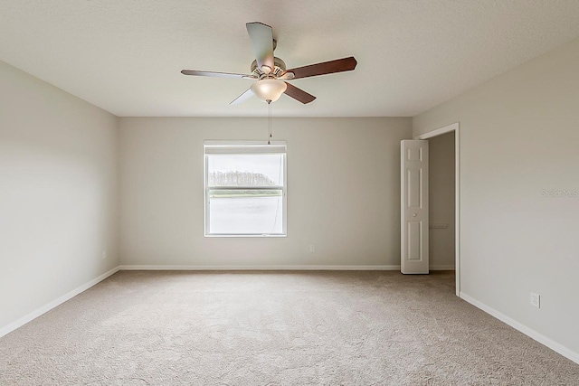 spare room featuring ceiling fan, baseboards, and carpet