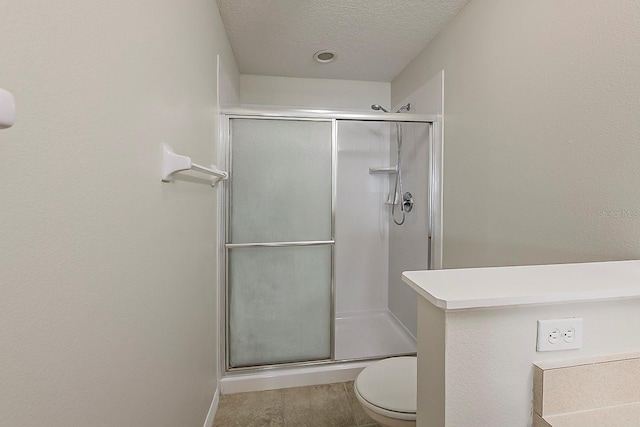 full bath with toilet, a stall shower, and a textured ceiling