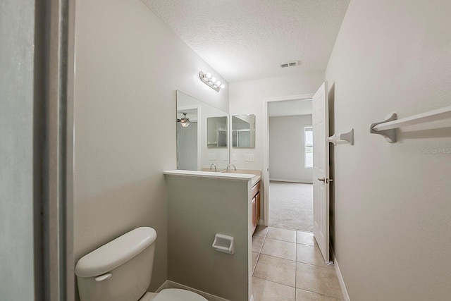 bathroom with visible vents, toilet, vanity, tile patterned floors, and a textured ceiling