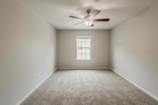 carpeted empty room with baseboards, a textured ceiling, and a ceiling fan