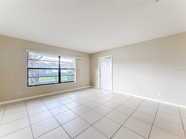 spare room featuring baseboards, a textured ceiling, and light tile patterned flooring