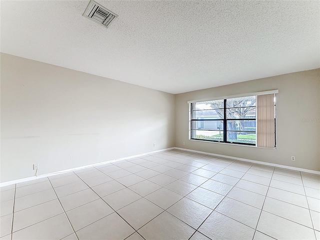 unfurnished room featuring visible vents, a textured ceiling, baseboards, and light tile patterned floors