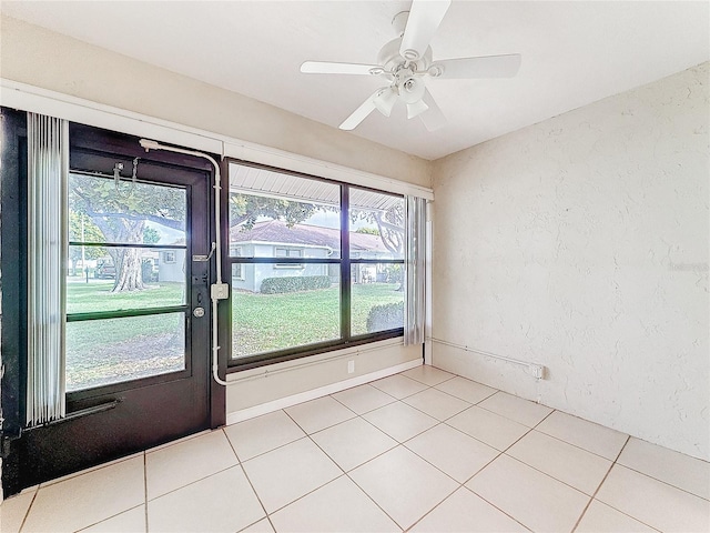 spare room with ceiling fan, light tile patterned flooring, and a textured wall