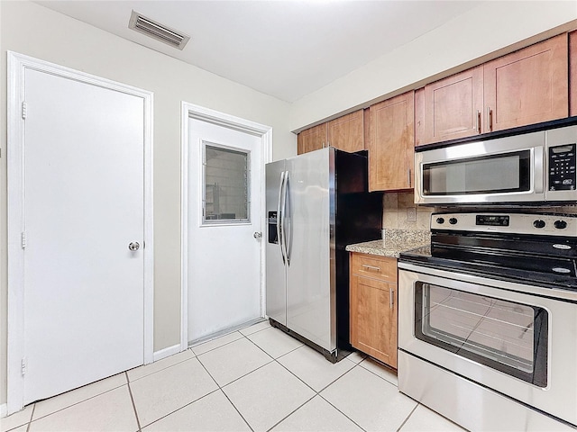 kitchen featuring light tile patterned floors, visible vents, appliances with stainless steel finishes, and brown cabinetry