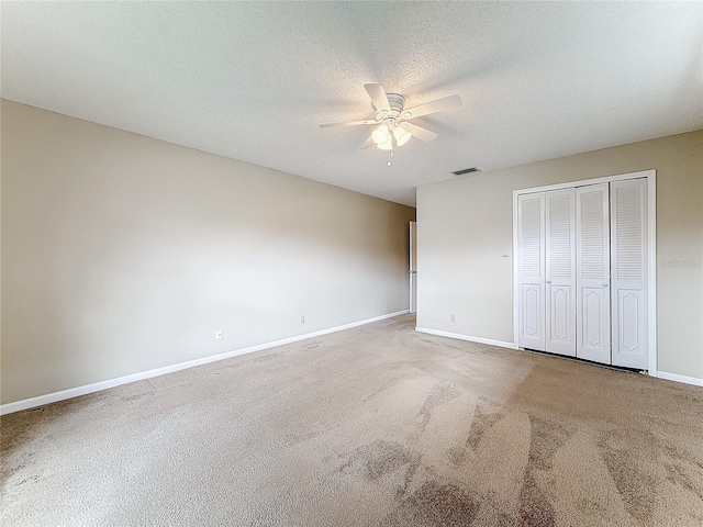 unfurnished bedroom with baseboards, visible vents, a textured ceiling, carpet flooring, and a closet