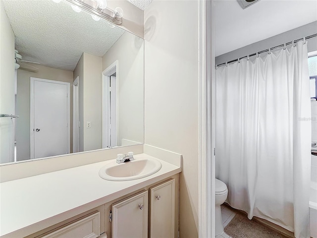 bathroom featuring a ceiling fan, toilet, a textured ceiling, and vanity