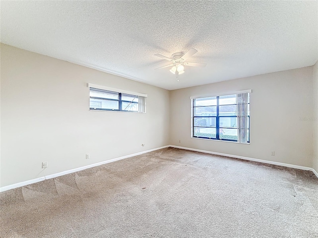 empty room featuring carpet, ceiling fan, a textured ceiling, and baseboards