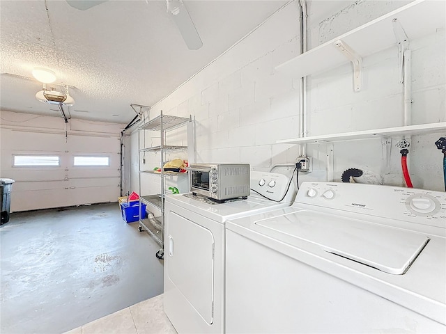 laundry room featuring a textured ceiling, a garage, laundry area, independent washer and dryer, and concrete block wall