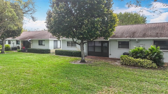 rear view of house with a yard, a shingled roof, cooling unit, and stucco siding