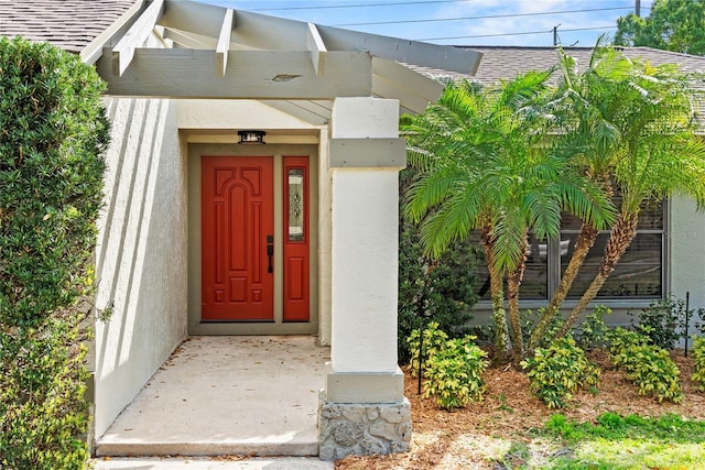 doorway to property with roof with shingles and stucco siding