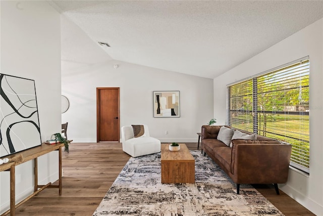 living room with lofted ceiling, a textured ceiling, wood finished floors, and visible vents