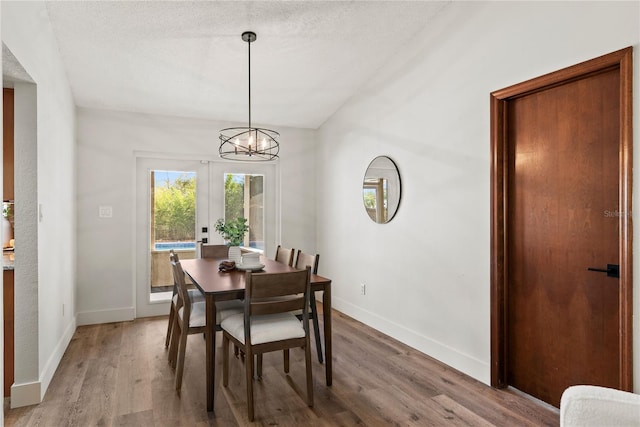 dining space featuring baseboards, french doors, a textured ceiling, and light wood-style floors