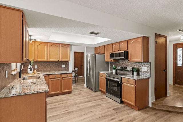 kitchen with a raised ceiling, visible vents, light wood-style flooring, decorative backsplash, and appliances with stainless steel finishes