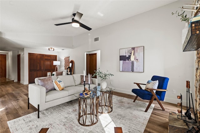 living area with baseboards, visible vents, a ceiling fan, wood finished floors, and vaulted ceiling